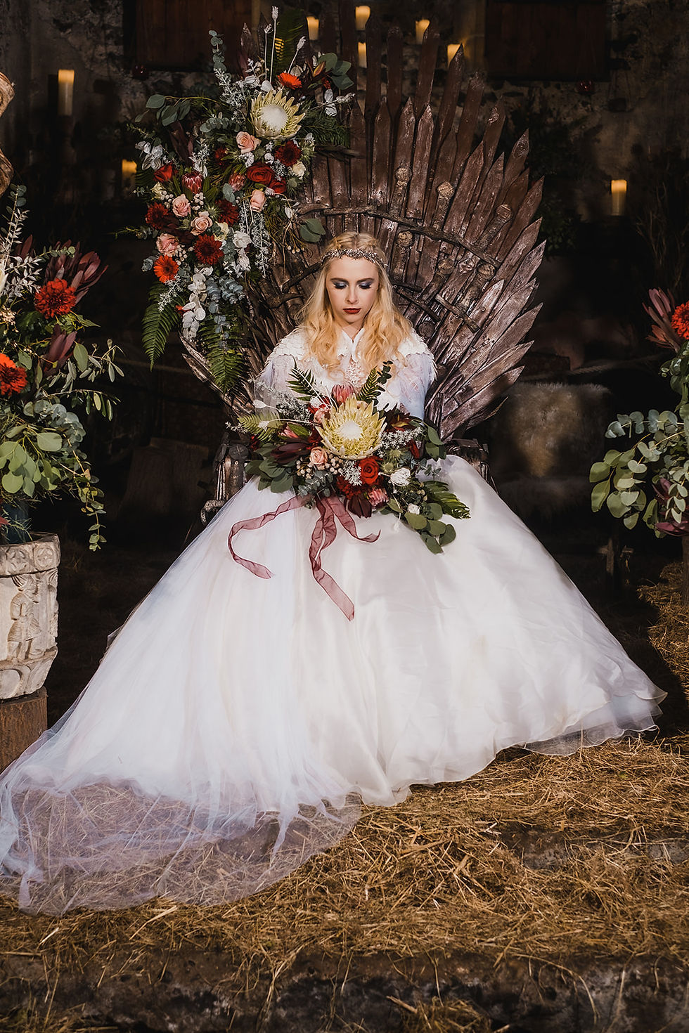A bride sitting on a throne of swords from Game of Thrones with a large bouquet
