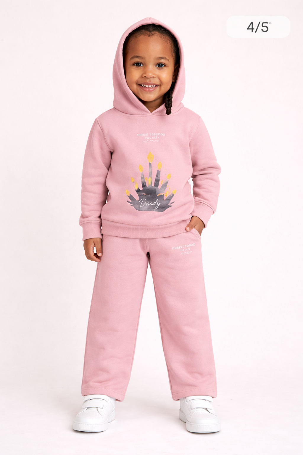 Smiling child in pink tracksuit, handprint candles