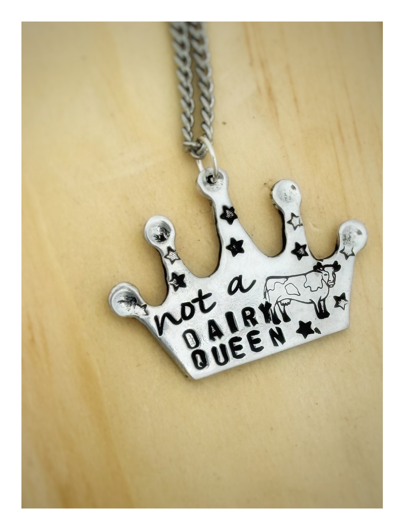 A handcrafted recycled aluminum crown necklace shimmering on a white surface