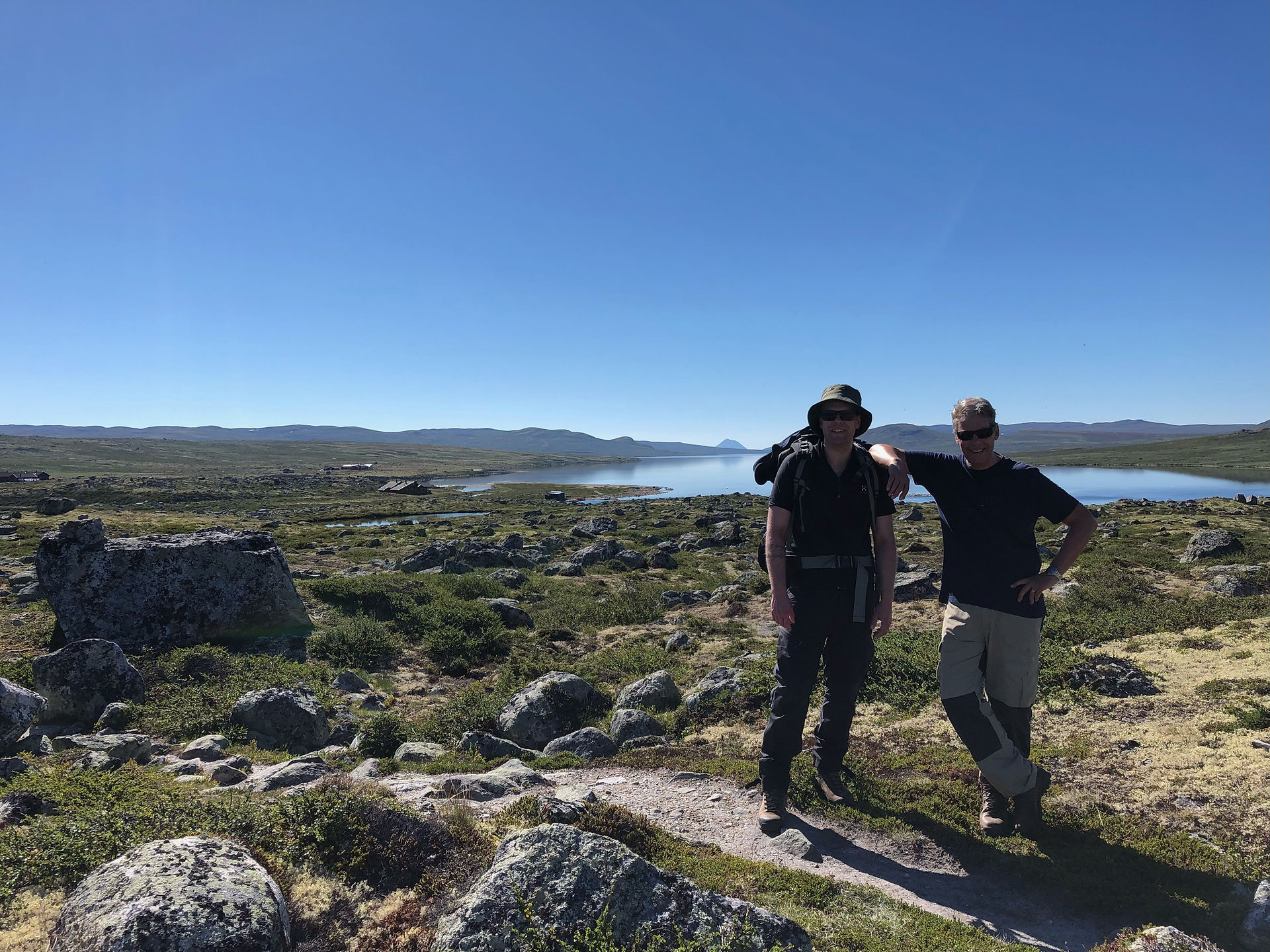 Lasse Pettersen og sønnen står med vannet Mår i bakgrunnen. Blå himmel