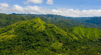 An expansive aerial shot of lush green mountain ridges in Bohol, Philippines, showcasing the island's diverse inland landscape on a signature Pearl Horizon tour.