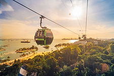 Scenic cable car ride in Singapore offering panoramic views of Sentosa Island, lush greenery, and the sparkling coastline at sunset.