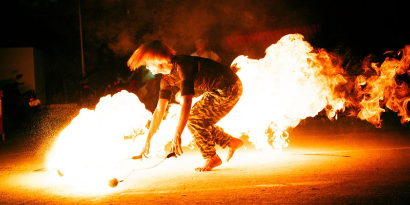 A fire performer twirls glowing fire poi and creates bursts of orange flames during an evening beachfront show on White Beach in Boracay, Philippines.