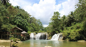 he gentle tiered cascades of Pangas Falls in Bohol, featuring a traditional nipa hut by the water's edge, perfect for an authentic Filipino riverside experience.
