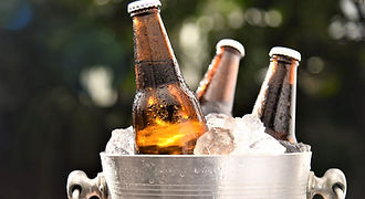 Three cold bottles of local Ayahay craft beer chilled in a silver ice bucket, offering a refreshing local beverage experience for tourists exploring Palawan island.