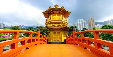 A bright orange wooden bridge leads toward the two-tiered golden Pavilion of Absolute Perfection inside Nan Lian Garden in Hong Kong.