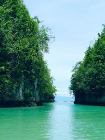 A traditional outrigger boat glides down the crystal-clear turquoise waters of Bojo River in Aloguinsan, Cebu, an award-winning community-based ecotourism destination.