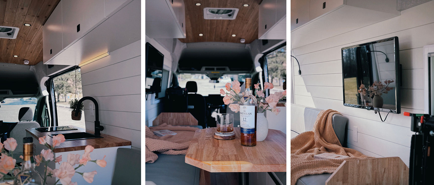 A detailed view of a camper van interior featuring a butcher block countertop and table, a spacious dinette with large grey faux leather seating, and a wall-mounted TV for entertainment.