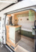 Transit custom build van's entryway with a full kitchen, generous overhead storage and under bench storage