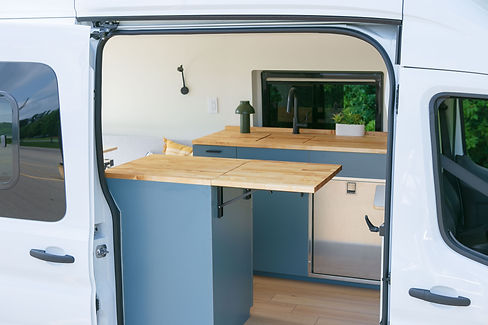 Apollo’s flip-up butcher-block counter extended across the open sliding doorway beside the blue kitchen galley.