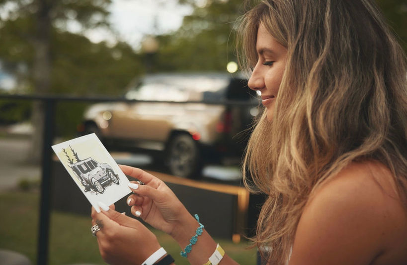 photograph of woman holding original artwork at Land Rover brand activation
