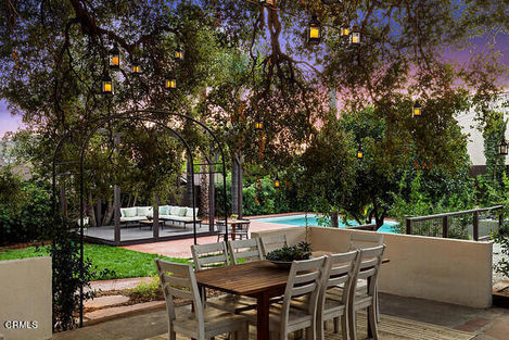 a patio with a table and chairs with lanterns hanging from the trees
