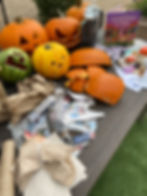Carved pumpkins and a watermelon sit on a table with scattered newspapers, napkins, and a book titled "The Wild West of Waste."