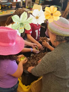 Children exploring a hands-on outdoor learning garden filled with plants and natural materials, supporting Montessori-inspired, nature-based education and sustainability learning.