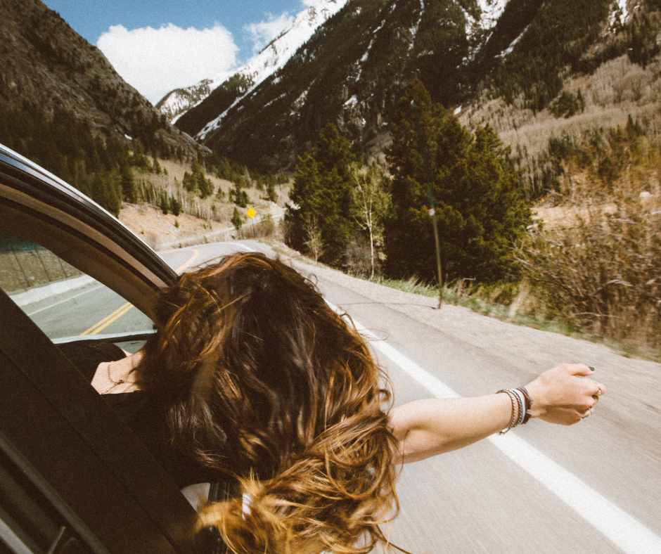 Woman leaning out window driving down mountain highway