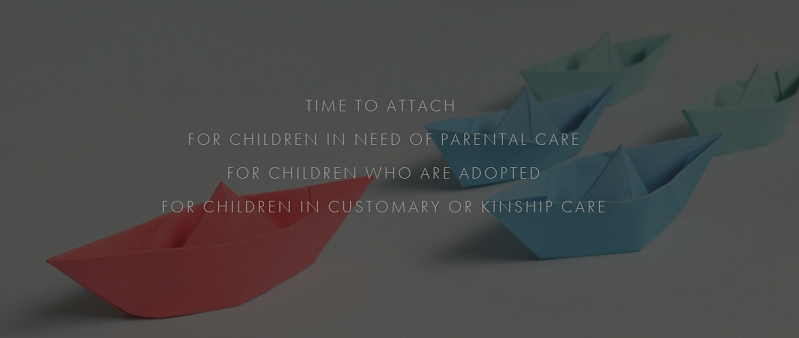 The image shows origami boats in bright colors, washed out with a grey overlay. White words read “Time to Attach. For children in need of parental care. For children who are adopted. For children in customary or kinship care.” The image is a screenshot from the Time to Attach website.