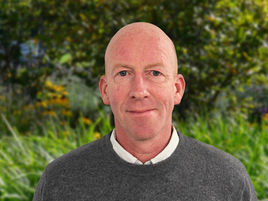 Tom Glancy in front of garden foliage background