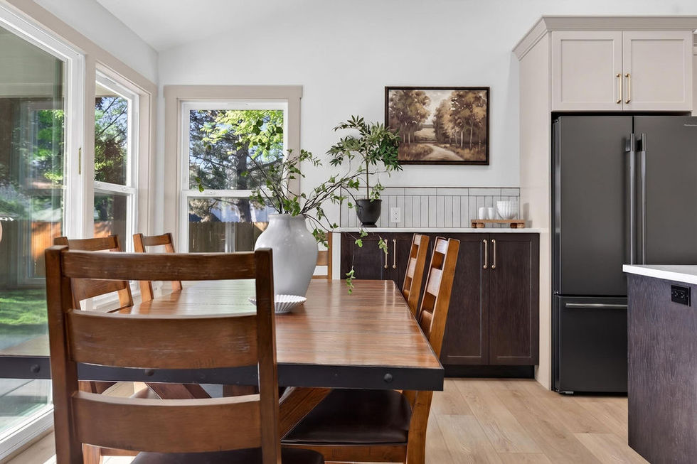 Dining room with wooden table and chairs, bright windows.
