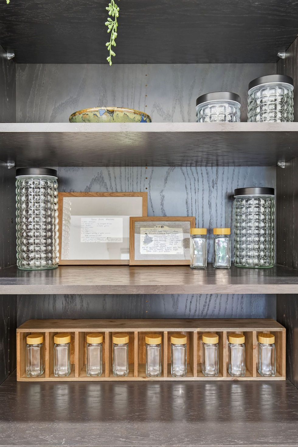 Organized shelves with jars and framed pictures.