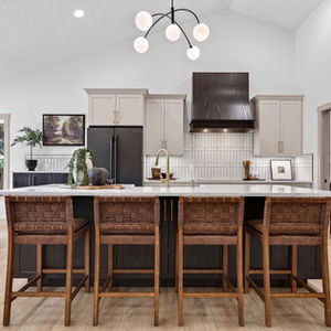 Modern kitchen with island and wicker bar stools.