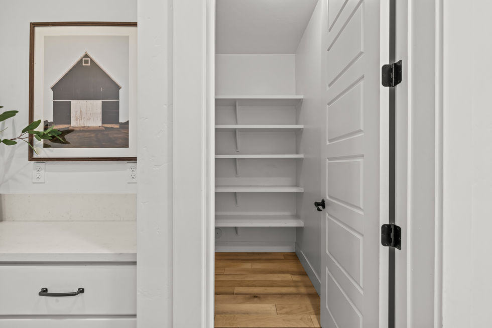 White pantry with wooden floor and shelves.