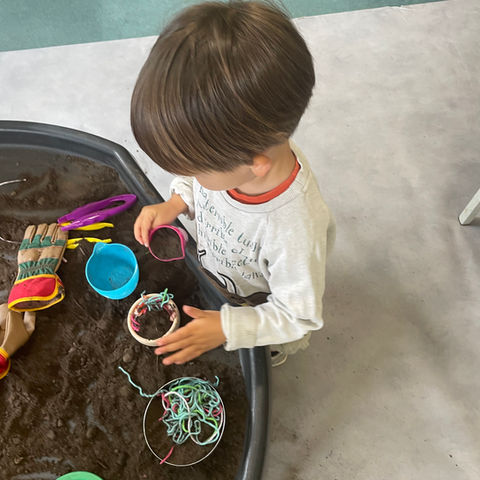 Boy playing with soil in tuff tray at Rodborough Playgroup