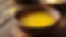 Close-up view of a bowl of golden desi cow ghee on a wooden surface