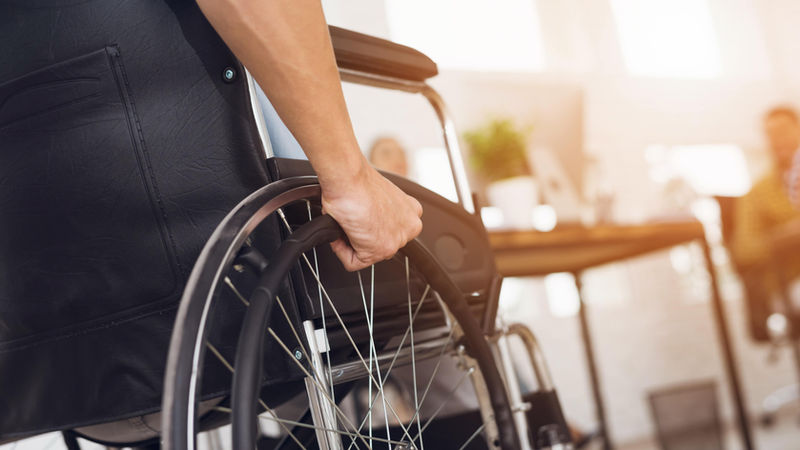 Una persona con disabilità in sedia a rotelle avanza in un ufficio