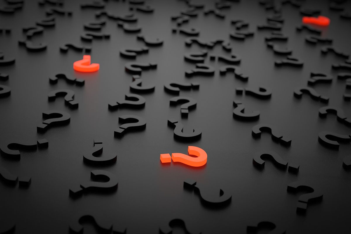 Illustrazione con dei punti interrogativi 3D su un tavolo nero, tutti di colore nero tranne tre di colore arancione fluo