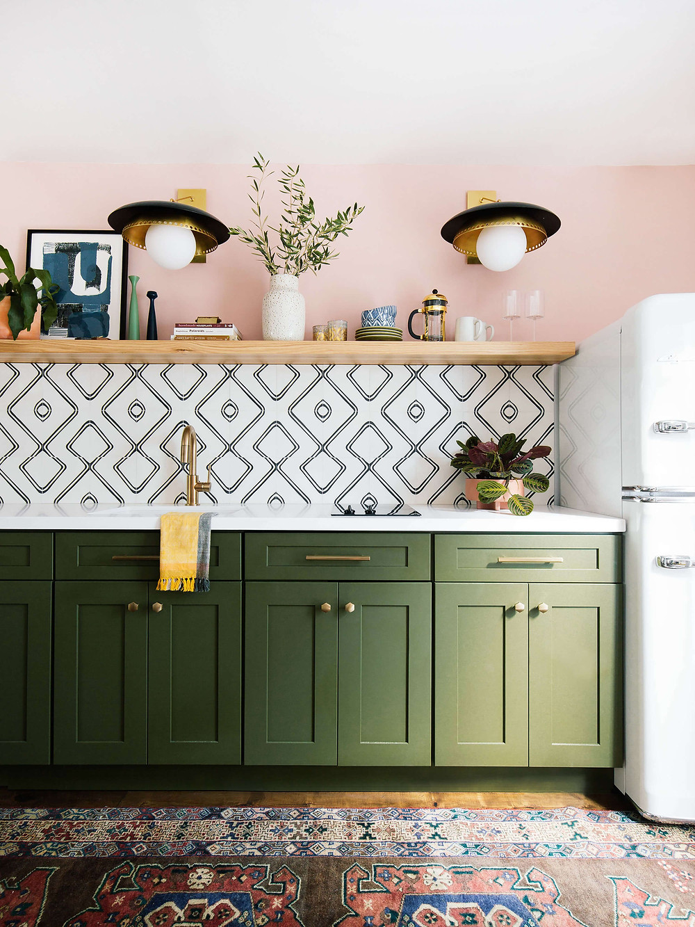 Green cabinets, pink walls, open shelving in guest house kitchen. Funky wall sconces, brass hardware and tap, fun tile back splash. Vintage style refrigerator. Vintage rug.