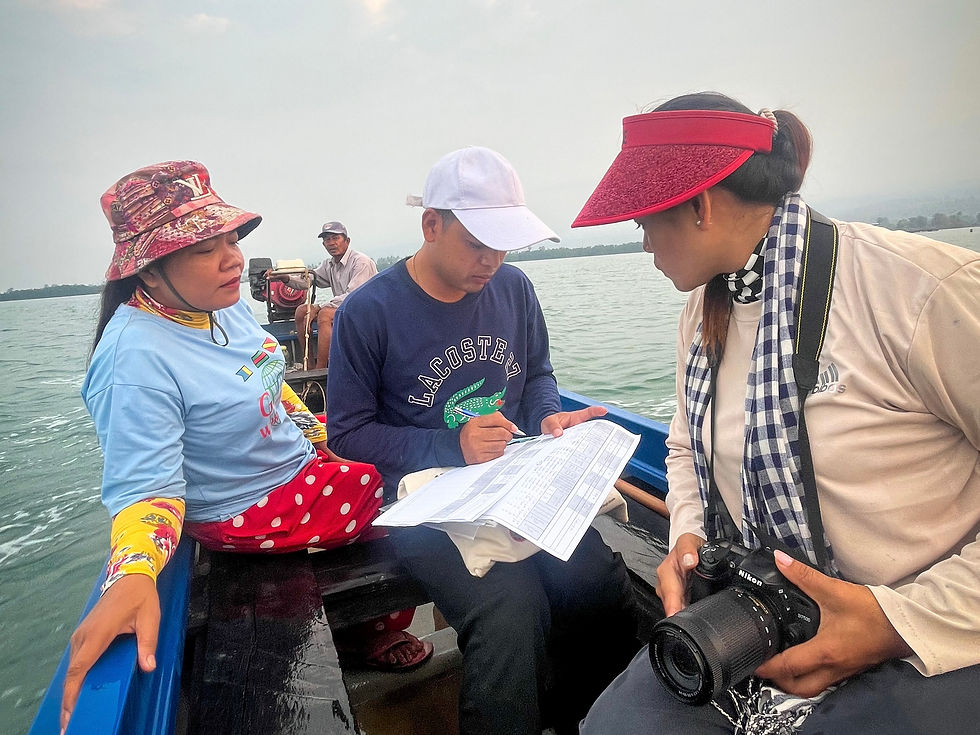 On a quiet boat, a circle of women lean towards the tide protecting the Irrawaddy dolphin