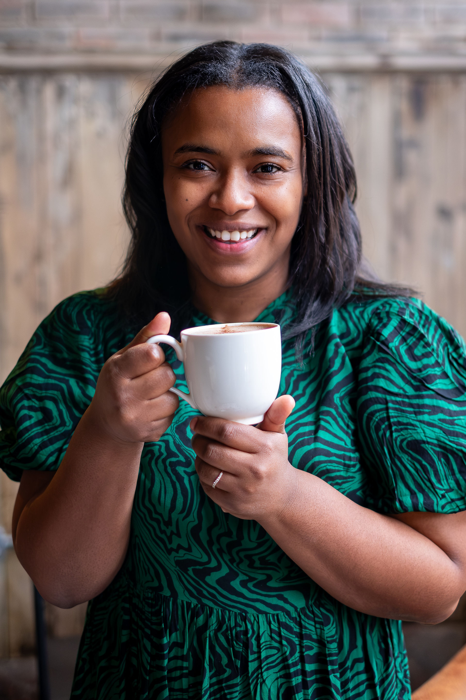 A woman in a green dress holding a cup of hot chocolate