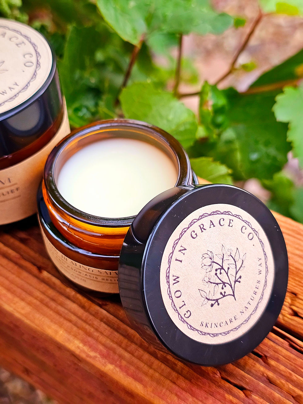 Thumbnail: Tallow bruise and wound salve in amber jar sitting in a garden with open lid
