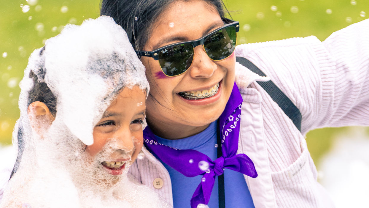 A Kids Ministry Dream Teamer smiles with a child covered in bubbles during a fun activity