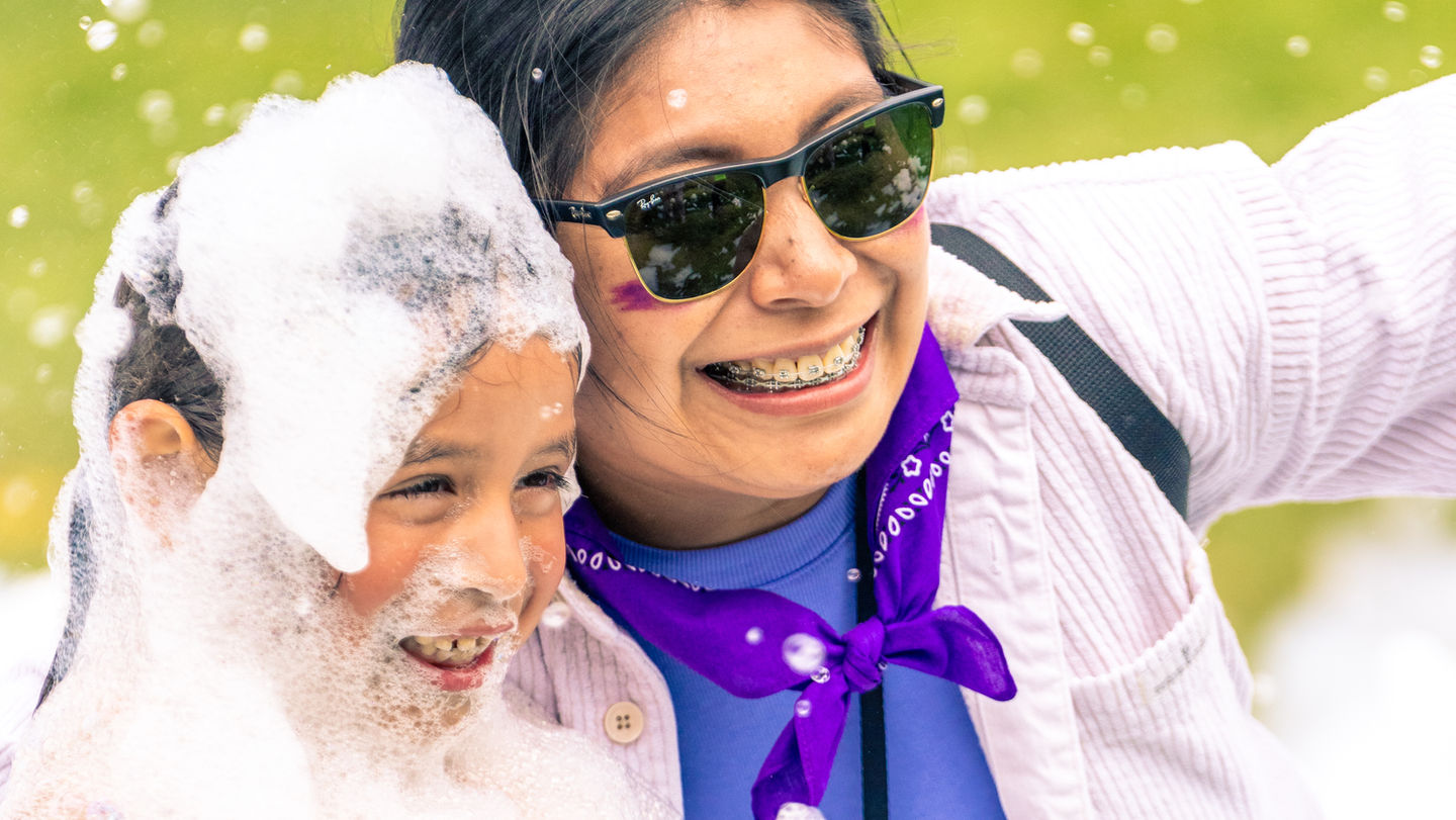 A Kids Ministry Dream Teamer smiles with a child covered in bubbles during a fun activity