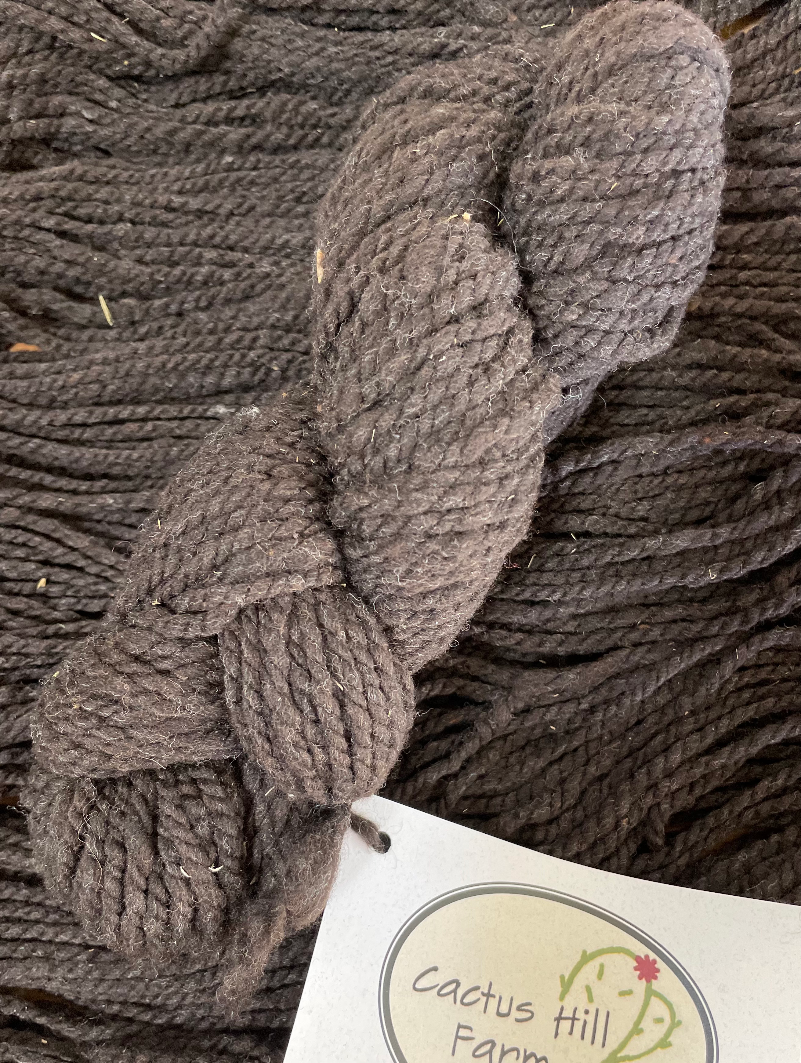 natural black merino bulky yarn skein with yarn in the background