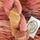Thumbnail: pink merino worsted yarn skein with yarn in the background