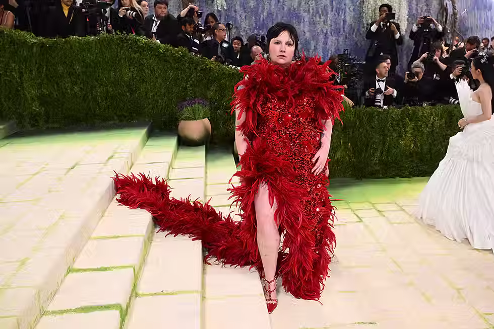 Lena Dunham at Met Gala 2026 wearing custom crimson Valentino Alessandro Michele gown with crow feathers and sequins inspired by Artemisia Gentileschi