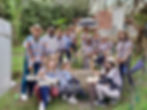Fifteen people in traditional clothing and one person with an umbrella