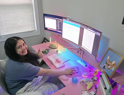 Lara Brooksbank sits at a pink desk, giving the camera a thumbs-up