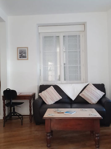 Living room with black leather couch, wooden table and white window