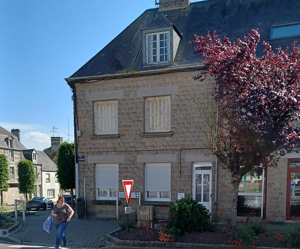 Woman walks toward a stone building with a yield sign on the street.