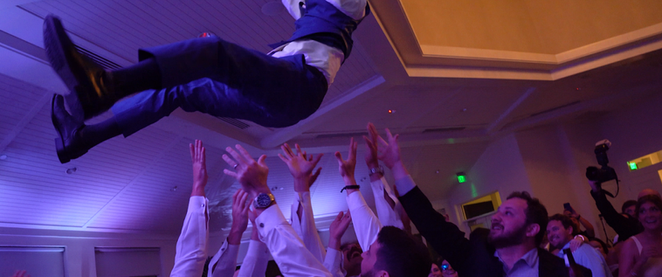 Bride’s father being tossed into the air by the wedding party outside St. Jude Catholic Church.