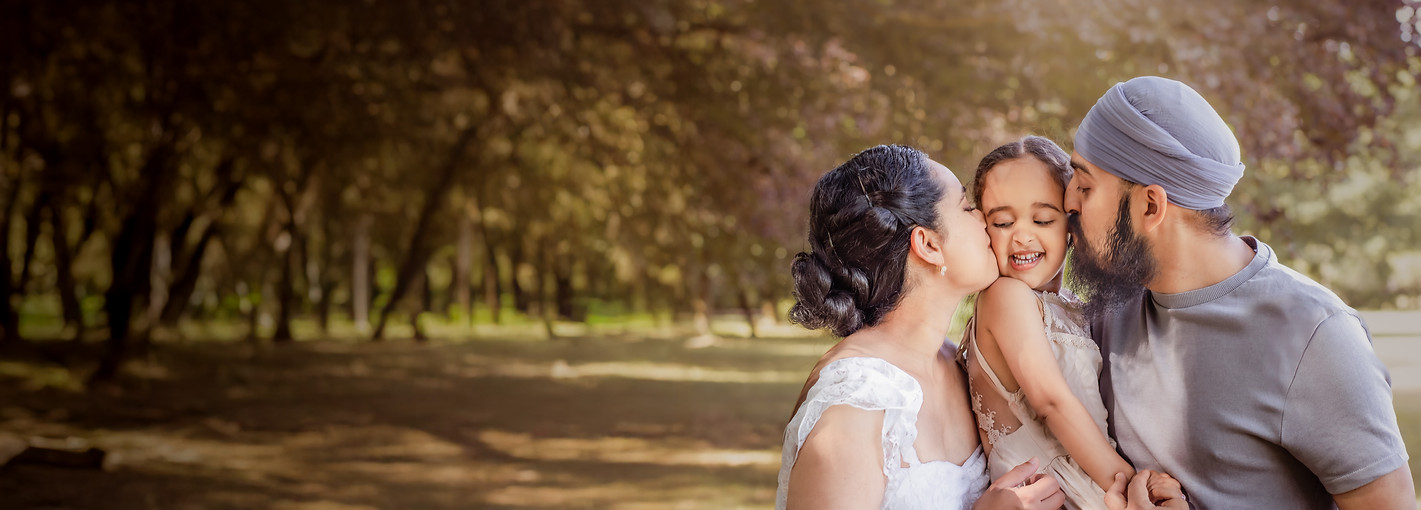 Parents kissing their daughter during an outdoor family photography session in Warwickshire