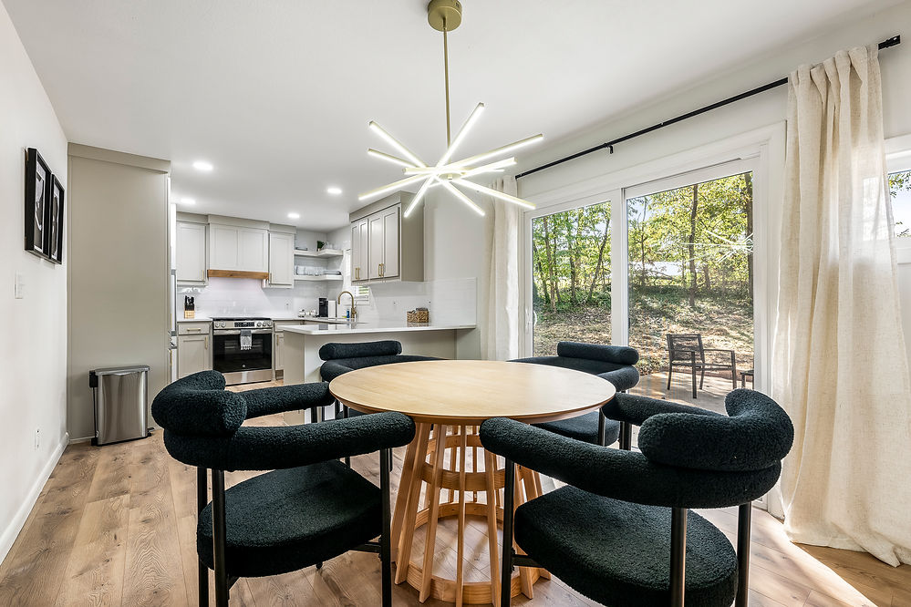 Dining room with round table, chairs and kitchen visible in the background.