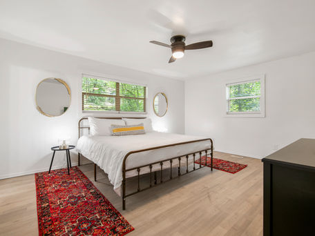 Bedroom with bed, mirrors, rug, and window views. Interior design, cozy atmosphere. Northern Pines Construction offers full home remodels