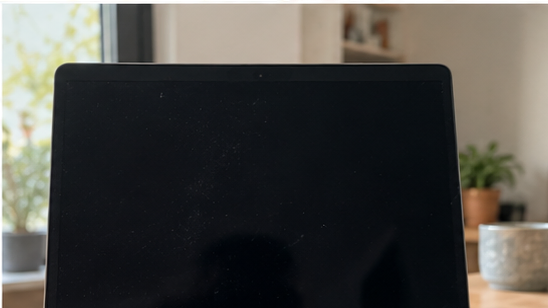 Ordinateur portable avec écran noir sur un bureau près d’une fenêtre