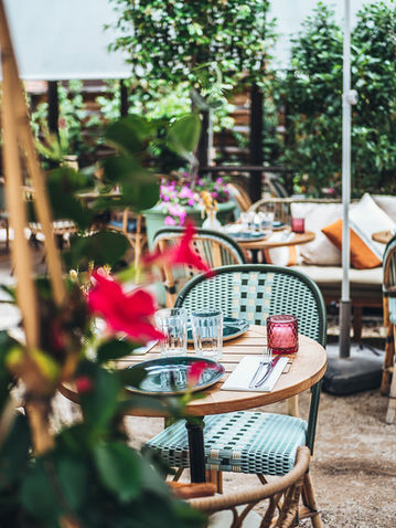Vue d'une terrasse ensoleillée avec mobilier en bois et fleurs, style bohème.