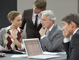 A group of 4 people sat around a table having a discussion