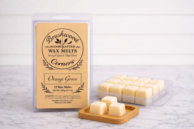 Handcrafted Orange Grove wax melts by Brushwood Corners in a clear clamshell with kraft label, displayed with wax cubes on a